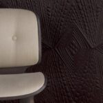Beige stoel voor donkerbruin Moooi Dwarf Rhino-behang met geometrisch reliëfpatroon.