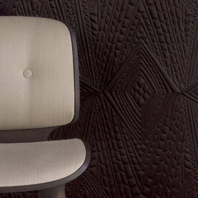 Beige stoel voor donkerbruin Moooi Dwarf Rhino-behang met geometrisch reliëfpatroon.