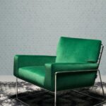Groene designfauteuil op een zwart-wit vloerkleed met Moooi-behang Flying Coral Fish op de achtergrond.