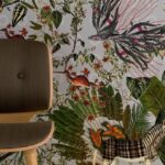 Behang met een fantasierijk junglepatroon uit de Moooi Menagerie of Extinct-collectie, naast een houten stoel met donkere stoffering.