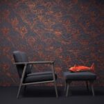 Donkerblauwe stoel en poef met een decoratieve oranje vis, voor een muur met Tokyo Blue Indigo Macaque-behang met koperkleurig patroon.