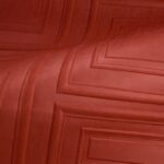 Close-up van een rood fluwelen oppervlak met een geometrisch reliëfpatroon uit de Objet Manoir 44020 M-KSQE-2 collectie.