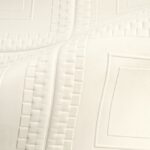 Detailopname van een lichtgekleurd, gewatteerd textiel met geometrisch reliëfpatroon uit de Objet Pantheon-collectie.