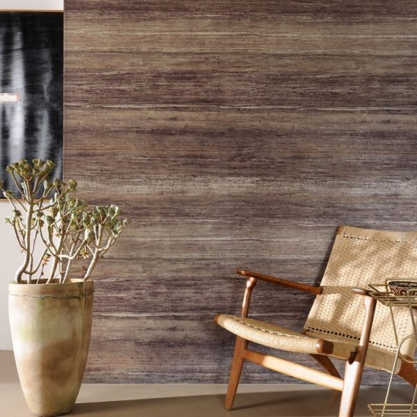 Rotan stoel en grote kamerplant voor een wand met houtstructuurbehang uit de Sinabaye-collectie.