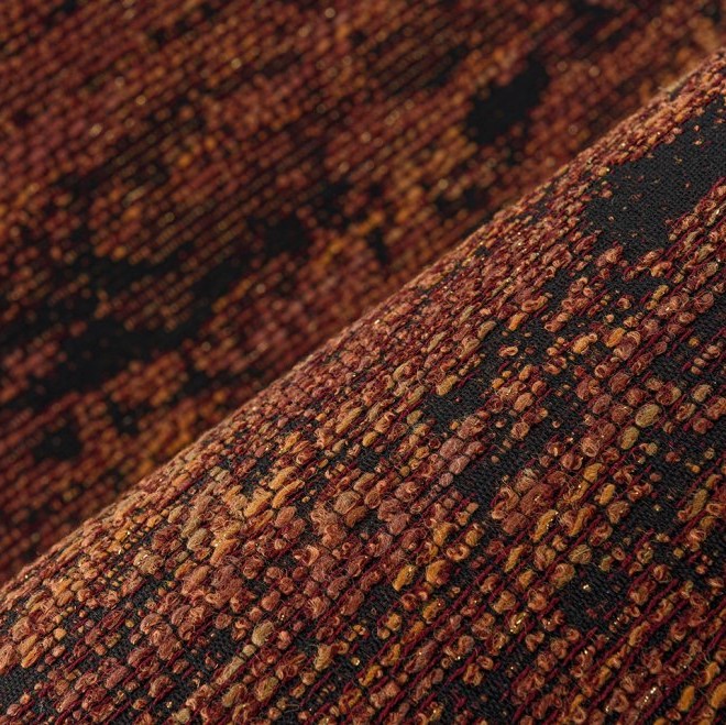 Close-up van de textuur van de Orrizonte3-EF7Y-2 meubelstof in warme roodbruine en zwarte tinten.
