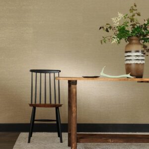 Houten tafel met vaas en takken naast een zwarte houten stoel tegen een beige Perles Jade muur.