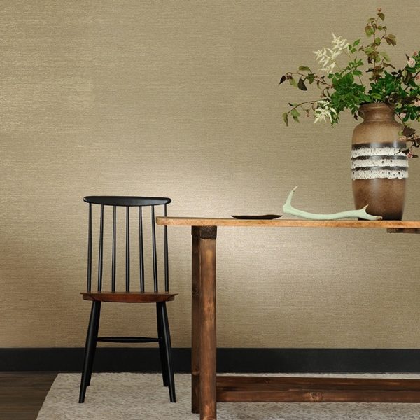 Houten tafel met vaas en takken naast een zwarte houten stoel tegen een beige Perles Jade muur.