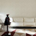 Modern interieur met een witte bank, geometrisch tapijt en een decoratief kunstobject in de kamer Perles Tourmaline.