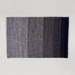Vloerkleed Perletta Limone Fade Blue met een verloop van licht- naar donkerblauwe banen in een geweven textuur.