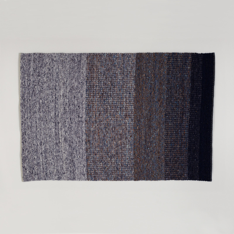 Vloerkleed Perletta Limone Fade Blue met een verloop van licht- naar donkerblauwe banen in een geweven textuur.