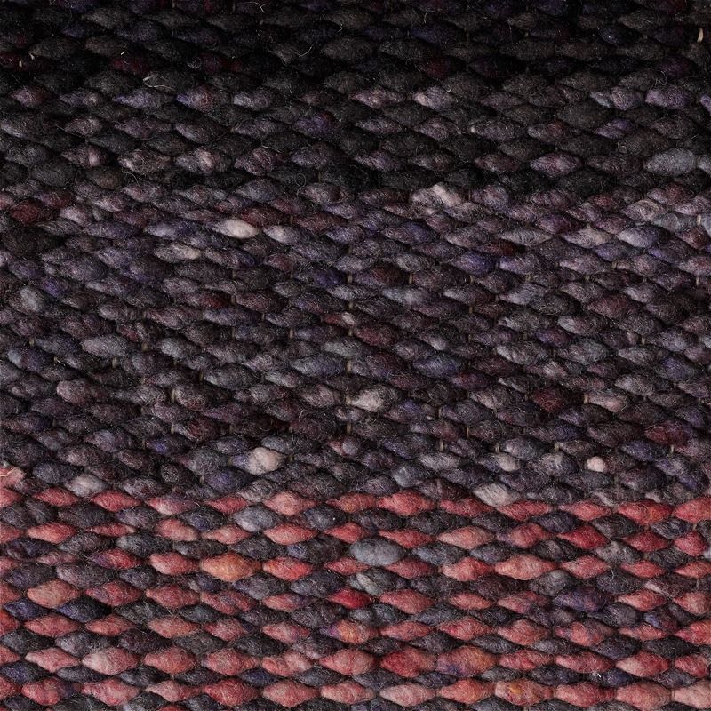 Detailopname van een grof geweven Perletta Limone vloerkleed in de kleur Fade Purple met paars-roze kleurverloop.