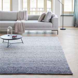 Sfeervolle woonkamer met een Perletta Limone Fade vloerkleed in grijsblauwe tinten voor een lichte bank en salontafel.