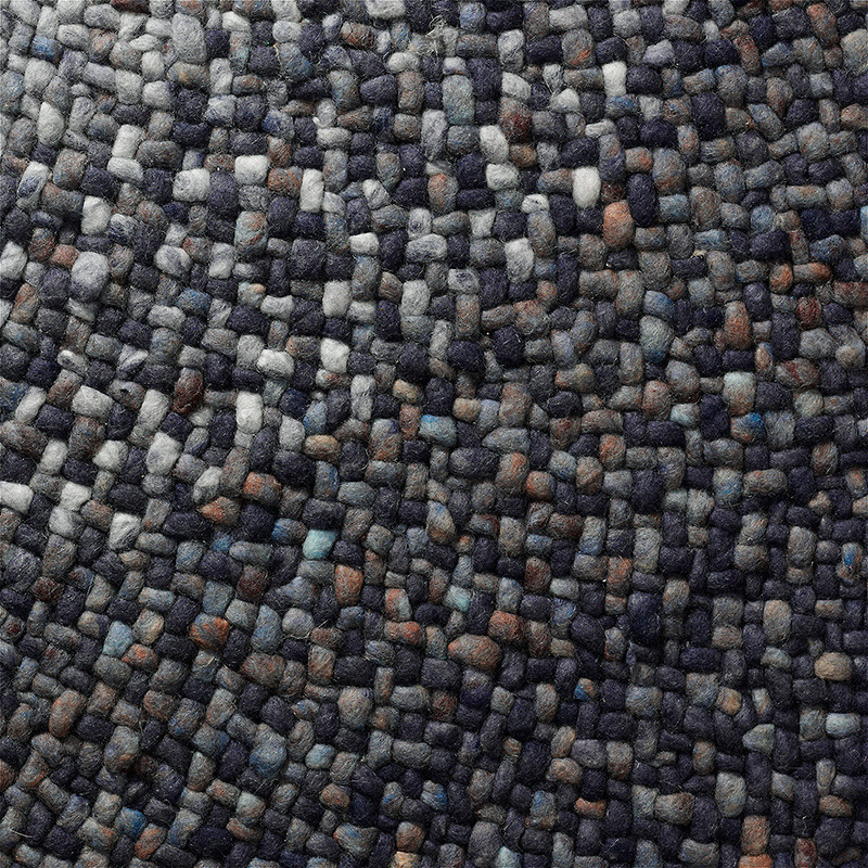 Detailopname van een geweven Perletta Roundabout Fade Blue vloerkleed met blauwgrijze en bruine kleuraccenten.