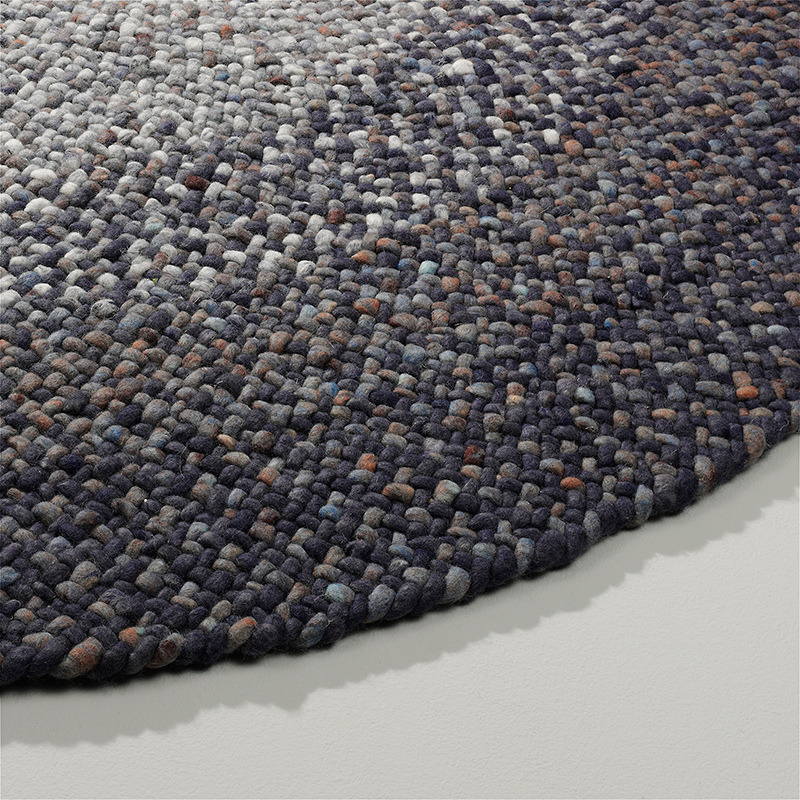 Rond geweven vloerkleed van Perletta in een blauw kleurverloop met grove textuur.
