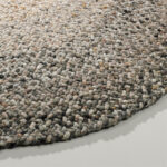 Detailopname van het ronde Perletta Roundabout Fade Brown vloerkleed met grove geweven textuur in bruine en grijze tinten.