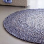 Rond, handgeweven Perletta Roundabout Fade vloerkleed in paarstinten in een moderne woonkamer.