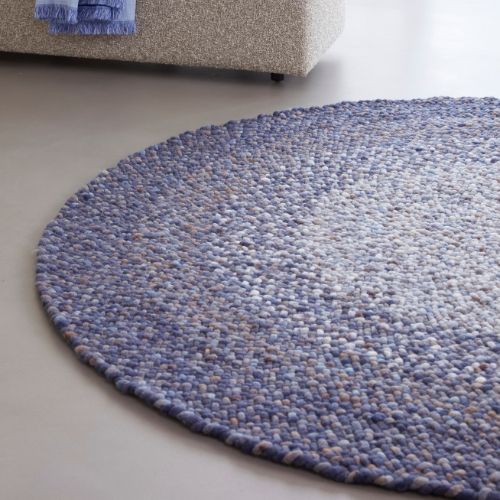 Rond, handgeweven Perletta Roundabout Fade vloerkleed in paarstinten in een moderne woonkamer.