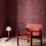 Moderne interieurhoek met rood Piante Arte-behang van Buningh, een rode designstoel en een bolvormige tafellamp.