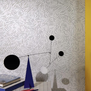 Moderne interieurhoek met Pierre Frey Diorama-behang FP-011001, geometrisch mobiel kunstobject en boeken op een geruit oppervlak.