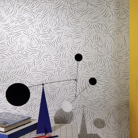 Moderne interieurhoek met Pierre Frey Diorama-behang FP-011001, geometrisch mobiel kunstobject en boeken op een geruit oppervlak.