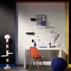 Moderne werkplek met Pierre Frey Diorama-behang, een wit bureau, designlamp en een oranje stoel.
