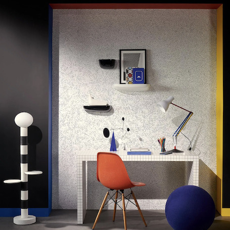 Moderne werkplek met Pierre Frey Diorama-behang, een wit bureau, designlamp en een oranje stoel.