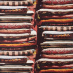 Gestapelde, kleurrijke kussens met etnische patronen in een bazaarstijl, gebaseerd op het Pierre Frey Le Grand Bazar ontwerp.