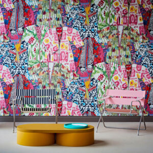 Kleurrijk Pierre Frey-behang FP626001 Manisa met een patroon van traditionele kledingstukken, achter moderne designstoelen en een ovale salontafel.