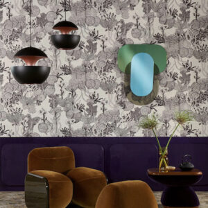 Interieur met Pierre Frey Punta Cana behang, bruinfluwelen stoelen, moderne hanglampen en een kleurrijke wandspiegel.