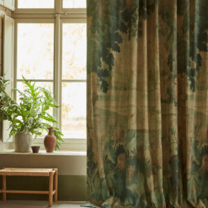 Gordijn van Pierre Frey-stof “Au Bord du Lac” met een natuurtafereel, hangend in een rustiek interieur met een houten bankje en aardewerken vazen.
