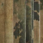 Close-up van geplooide Pierre Frey-stof ‘Au Bord du Lac’ met een natuurprint in groentinten.