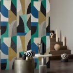 Kleurrijk geometrisch behang uit de Puzzle2-I7A4-2 serie in een modern interieur met decoratieve objecten en bijzettafels.