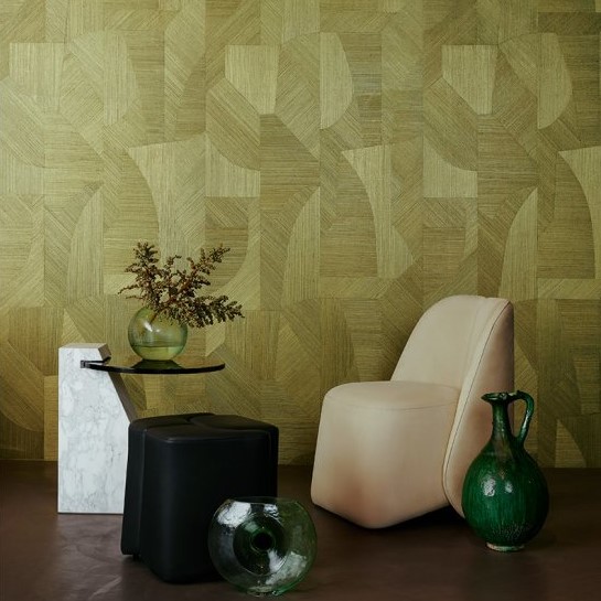 Modern interieur met een geometrisch groen behang (Puzzle3-3019-2), een crèmekleurige stoel, zwarte en marmeren bijzettafels en groene glazen decoratieobjecten.