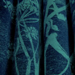 Donkerblauwe stof met een lichtgroen botanisch patroon en verticale plooien.