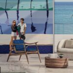 Luxe interieur met een Elitis-muurschildering van een stijlvol stel aan het strand en moderne houten meubels op een glanzende vloer.