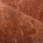 Close-up van een rol roodbruin stucwerkbehang met een gemarmerde textuur.