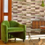Groene VP-425 loungefauteuil op wieltjes in een retro-interieur met geometrisch behang en houten accenten.