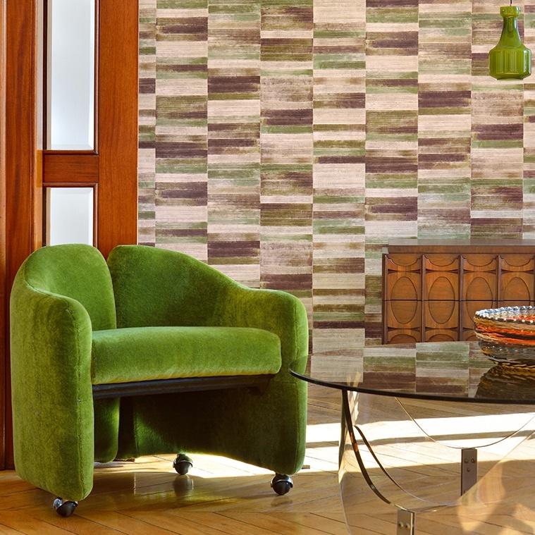 Groene VP-425 loungefauteuil op wieltjes in een retro-interieur met geometrisch behang en houten accenten.
