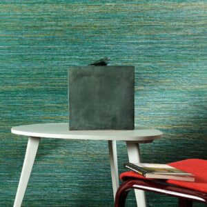 Moderne interieursetting met groen-blauw VP-712-05 behang, een witte tafel, decoratief beeld en rode stoel met boeken.