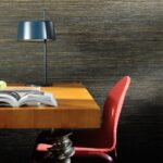 Moderne werkplek met houten bureau, rode stoel, zwarte tafellamp en een open tijdschrift tegen een donker gestreepte VP-712 muur.