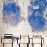Drie metalen stoelen staan voor een muur met abstracte blauwe verfvlakken, aangeduid als VP-881-01-1.