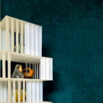 Moderne witte wandkast Alcove 2 met decoratieve objecten tegen een diepblauwe muur.