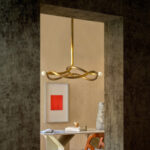 Modern ingerichte nis met de Alcove 2 Garçonnière RM 1063-67 hanglamp, boven een stijlvolle tafel met kunst en designobjecten.
