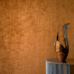 Keramisch kunstobject op een ronde metalen tafel voor een warmbruine Alcove 2 RM 41070 wandbekleding.
