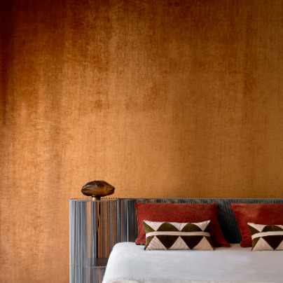 Sfeervolle slaapkamer met Alcove 2 RM 410-70 fluwelen wandbekleding, een gestreept hoofdbord en decoratieve kussens.