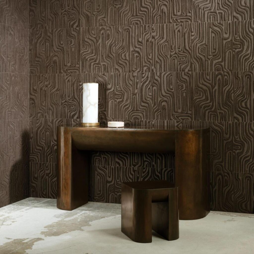 Bronzen tafel en kruk voor een muur bekleed met het donkerbruine, abstracte reliëfbehang Arte Cloud 30832.