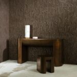 Bronzen tafel en kruk voor een muur bekleed met het donkerbruine, abstracte reliëfbehang Arte Cloud 30832.