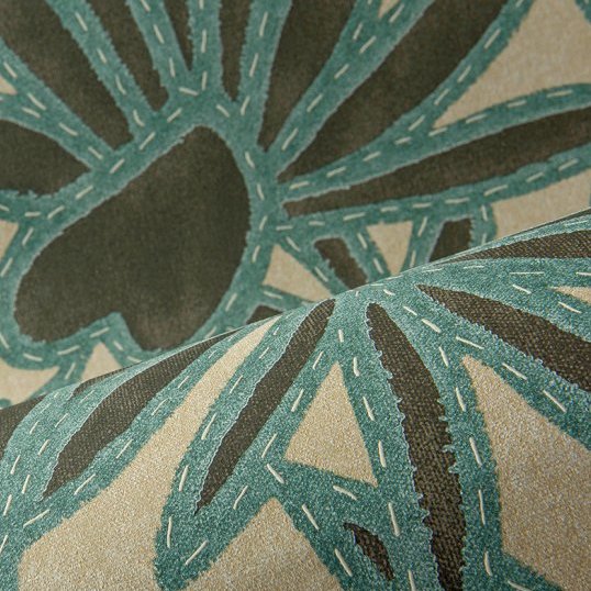Close-up van Arte behang Botanis 57581 Nutmeg Teal met een botanisch patroon in groenblauw en bruin op een beige achtergrond.