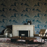 Sfeervolle woonkamer met blauw Arte Lanai Maui 81530 behang met palmbladmotief achter een natuurstenen haard.