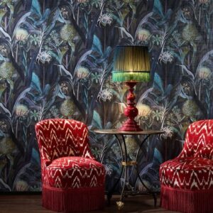Twee rood met wit gestoffeerde stoelen en een rood tafeltje met groene lamp voor een donker bloemrijk Arte Blooming Pineapple behang.